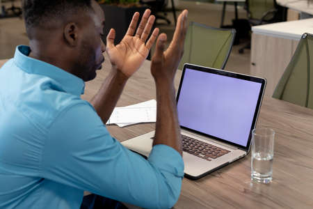 African american businessman on video call through laptop with copy space on screen at desk....