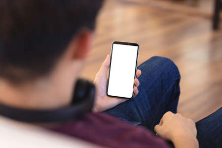 High angle midsection of asian teenage boy using smartphone while sitting in living room, copy...