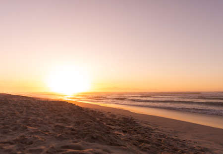 Scenic view of sandy beach and waves in sea against clear sky during sunset, copy space. unaltered,...
