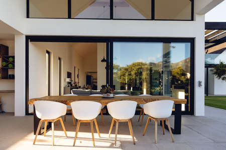 View of luxurious modern house exterior with dining space and garden. Modern architecture and...