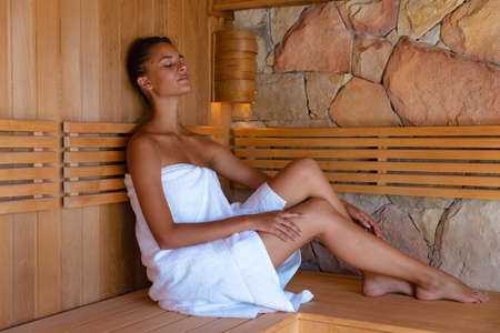 Caucasian young woman in a bathrobe relaxing in the sauna. Spa, wellness and relaxation conceptの写真素材