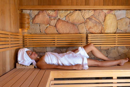 Caucasian young woman in a bathrobe relaxing in the sauna. Spa, wellness and relaxation conceptの写真素材