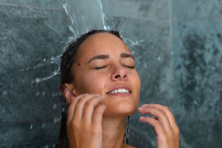 Close up of caucasian young woman taking a shower in the bathroom at home. Self-care, hygiene and relaxation conceptの写真素材