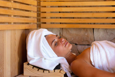 Caucasian young woman in a bathrobe relaxing in the sauna. Spa, wellness and relaxation conceptの写真素材