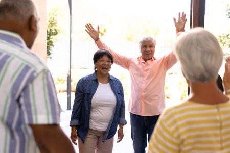 Biracial seniors male and female welcoming cheerful friends in nursing home, copy space. Entrance, guest, greeting, happy, togetherness, unaltered, support, assisted living and retirement.の写真素材