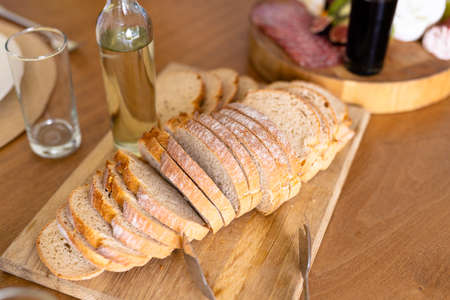 High angle view of bread slices served on board with drinking water bottle and glass on dining...