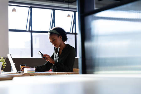 African american young businesswoman using smart phone in office. Unaltered, creative business,...