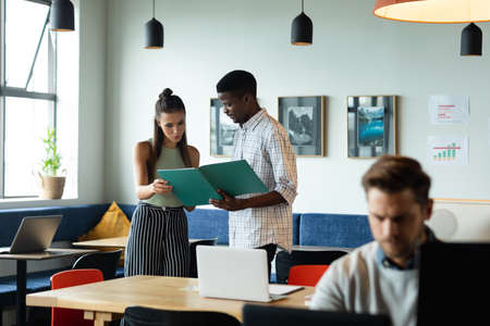 Caucasian businesswoman and african american businessman discussing strategy over file in office....