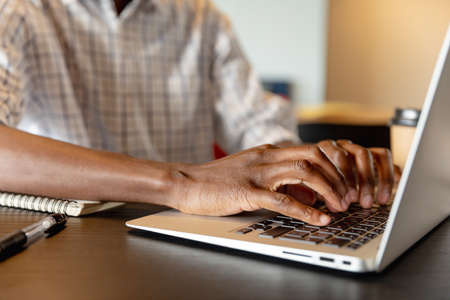 Midsection of african american young businessman using laptop in creative office. Unaltered, creative business, workplace, occupation, wireless technology.の写真素材