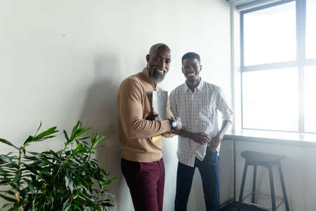 Portrait of smiling african american businessmen standing in creative office. Unaltered, creative...