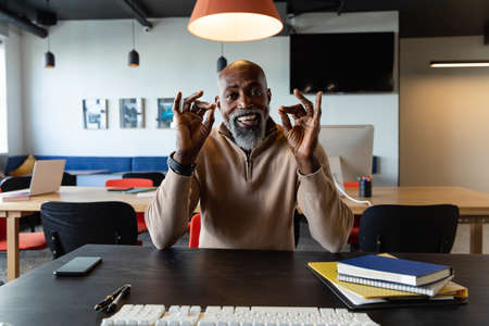 Portrait of african american mature businessman discussing on video call in office. Unaltered,...