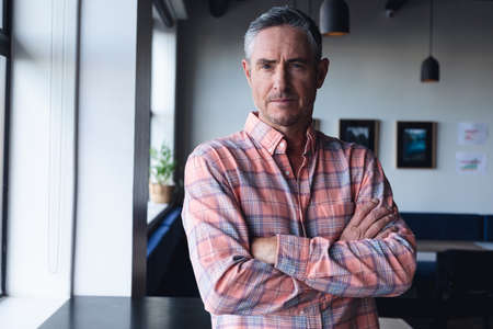 Portrait of confident mature caucasian businessman in creative office. Unaltered, creative business, workplace, occupation, serious, attitude.の写真素材