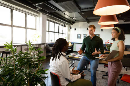 Caucasian manager discussing with multiracial colleagues in meeting at office. Unaltered, creative...