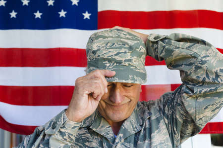 Close-up of smiling caucasian army soldier wearing camouflage cap against flag of america....