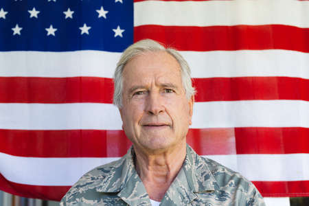 Close-up portrait of caucasian army soldier wearing camouflage clothing against flag of america. Copy space, confidence, unaltered, senior, pride, military, armed forces and patriotism concept.の写真素材