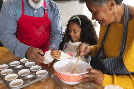 Image of happy african american grandparents and granddaughter baking in kitchen. Family and spending quality time together concept.の写真素材