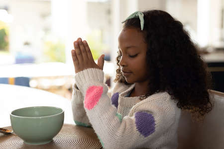 Image of african american girl praying before meal. Childhood, religion and spending time at home concept.の写真素材