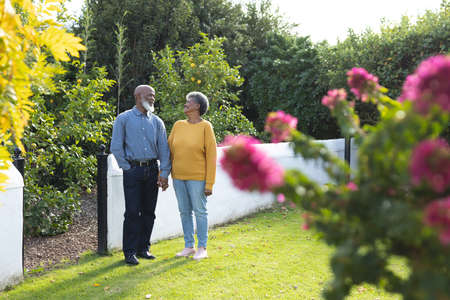 Image of happy african american senior couple walking in garden. Family and spending quality time together concept.の写真素材