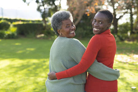 Image of happy african american mother and adult daughter posing in garden. Family and spending...