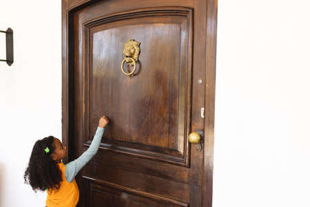 Image of african american girl in halloween costume knocking on doors. Halloween, american culture and celebration concept.の写真素材