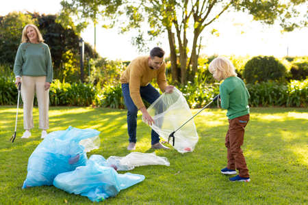 Image of happy multi generation caucasian family collecting waste in garden. Family and spending...