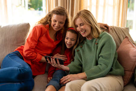 Image of happy three generation caucasian women sitting on sofa and taking selfie. Family and...