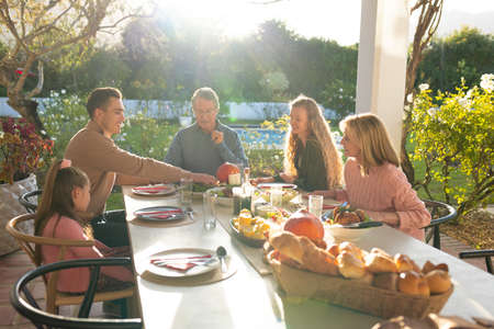 Image of multi generation caucasian family eating outdoor dinner. Family and spending quality time together concept.の写真素材