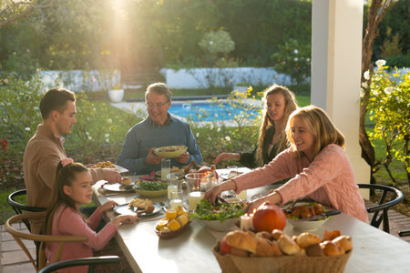 Image of multi generation caucasian family eating outdoor dinner. Family and spending quality time together concept.の写真素材
