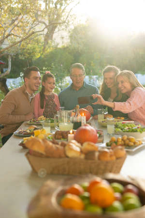 Vertical image of multi generation caucasian family taking selfie after outdoor dinner. Family and spending quality time together concept.の写真素材