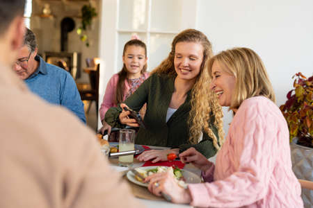 Image of multi generation caucasian family dining and using smartphone. Family and spending quality...