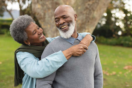 Image of happy african american senior couple posing at camera outdoors in autumn. Family, spending...