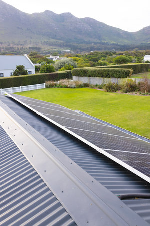 Solar panels on rooftop and scenic view of lush landscape and mountain against clear sky, copy...
