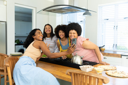 Happy young woman taking selfie with biracial female friends over smartphone while enjoying at home....