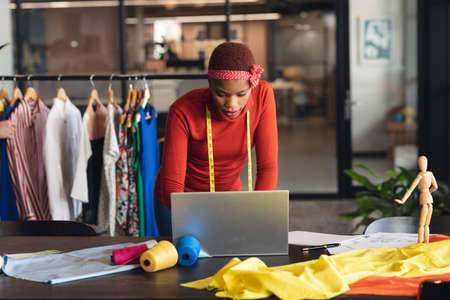 African american fashion designer working on laptop at desk in studio office. Unaltered, creative...