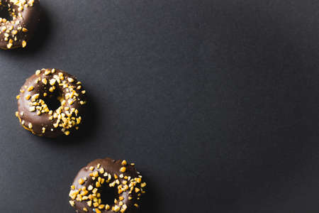 High angle view of chocolate donuts with crumbs by copy space on black background. unaltered, unhealthy eating and sweet food concept.の写真素材