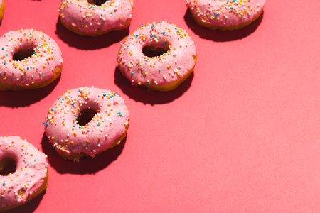 High angle view of copy space by sprinklers on fresh donuts over pink background. unaltered, unhealthy eating and sweet food concept.の写真素材