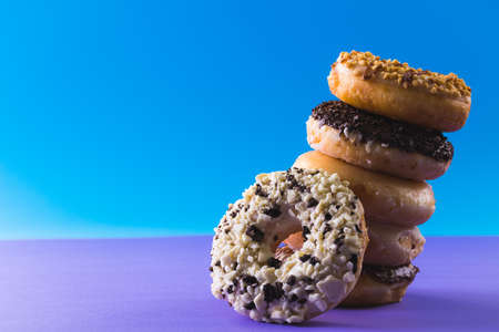 Close-up of fresh donuts stacked tilted by copy space against blue background. unaltered, unhealthy eating and sweet food concept.の写真素材