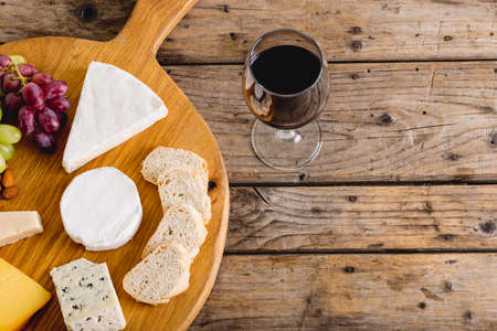 Overhead view of various cheese with grapes and red wine on wooden table, copy space. unaltered, food, fruit, drink, alcohol and dairy product.の写真素材
