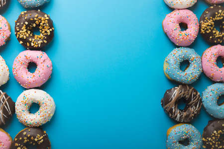 Directly above view of copy space amidst various fresh donuts against blue background. unaltered,...
