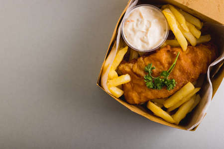 Directly above shot of french fries and seafood with sauce in box over gray background, copy space. unaltered, food, fried food, ready-to-eat, studio shot and meal.の写真素材