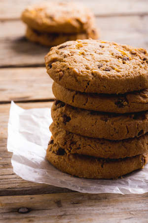 Close-up of cookies stacked on parchment paper at wooden table, copy space. unaltered, food, baked...