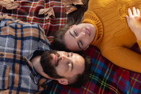 Image of happy caucasian couple lying on blanket in autumn garden. Love, relationship, spending...