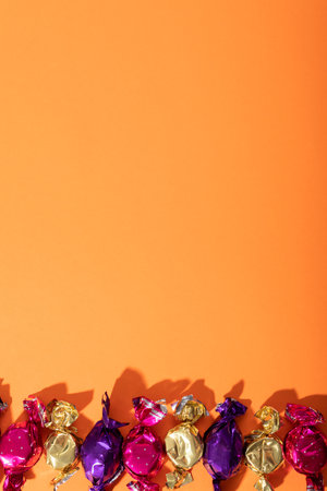 Close up of multiple halloween candies with copy space against orange background. fall season and celebration conceptの写真素材