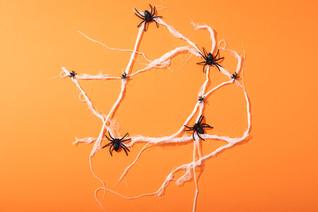 Multiple spider toys forming a spider web with copy space against orange background. fall season and celebration conceptの写真素材