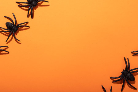 Close up of multiple spider toys with copy space against orange background. fall season and celebration conceptの写真素材