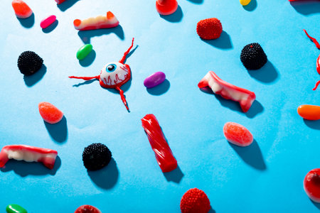 Multiple scary eyes toys and halloween candies on blue surface. fall season and celebration conceptの写真素材