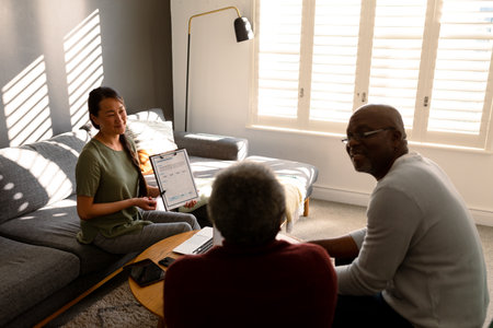 African american senior couple having meeting with asian female financial advisor at home. retirement lifestyle, elderly support and spending time at home.の写真素材