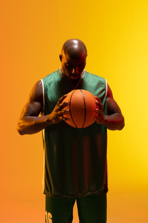 Image of african american basketball player with basketball on neon orange background. Sports and competition concept.の写真素材