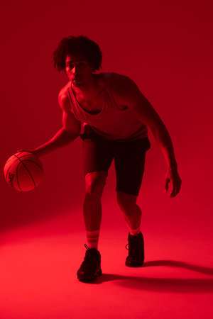 Image of biracial basketball player with basketball on neon red background. Sports and competition concept.の写真素材