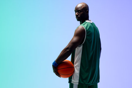 Image of african american basketball player with basketball on green to blue background. Sports and competition concept.の写真素材